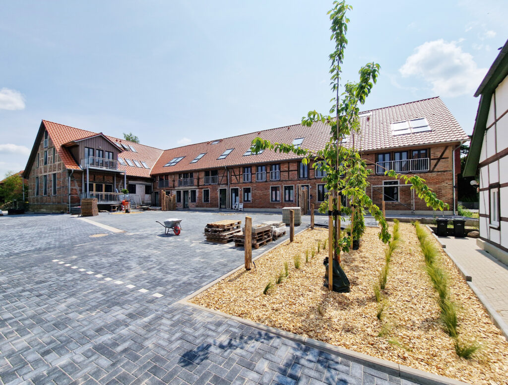 ofansicht nach der Sanierung mit gepflastertem Innenhof, Begrünung und Blick auf die sanierten Fachwerkgebäude mit Dachfenstern